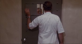 Movie still from “High Anxiety” (1977), directed by Mel Brooks – A man in a white lab coat looking in a mirror; Medium shot, Over the shoulder angle