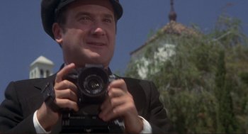 Movie still from “High Anxiety” (1977), directed by Mel Brooks – A man holding a camera in front of a building; Close Up shot, Low angle