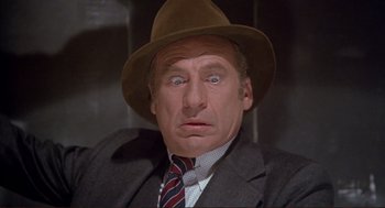Movie still from “High Anxiety” (1977), directed by Mel Brooks – A person wearing a suit and a hat; Close Up shot, High angle