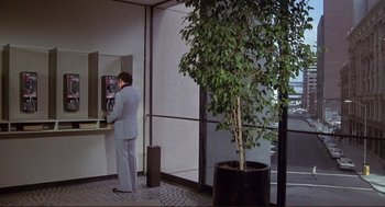 Movie still from “High Anxiety” (1977), directed by Mel Brooks – A man standing in front of an atm machine next to a tree; Wide shot, High angle