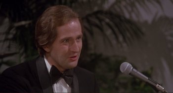 Movie still from “High Anxiety” (1977), directed by Mel Brooks – A man in a tuxedo is talking into a microphone; Close Up shot, Over the shoulder angle
