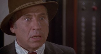 Movie still from “High Anxiety” (1977), directed by Mel Brooks – An older man wearing a suit and a hat; Close Up shot, Over the shoulder angle