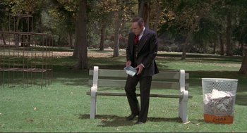 Movie still from “High Anxiety” (1977), directed by Mel Brooks – A man in a suit and tie sitting on a park bench; Wide shot, High angle