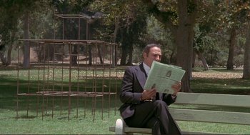 Movie still from “High Anxiety” (1977), directed by Mel Brooks – A man sitting on a park bench reading a newspaper; Wide shot, Low angle