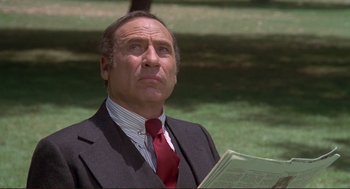 Movie still from “High Anxiety” (1977), directed by Mel Brooks – An older man wearing a suit and tie holding a book; Close Up shot, Low angle