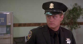 Movie still from “High Anxiety” (1977), directed by Mel Brooks – A police officer in a uniform is sitting in a room; Close Up shot, Over the shoulder angle
