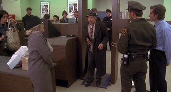 Movie still from “High Anxiety” (1977), directed by Mel Brooks – A man in a suit and tie standing in front of a group of people; Wide shot, High angle