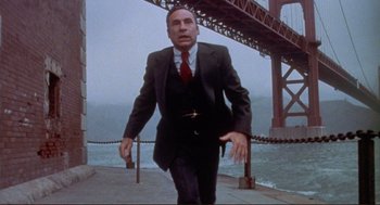 Movie still from “High Anxiety” (1977), directed by Mel Brooks – A man in a suit and tie walking on a bridge; Medium shot, Low angle