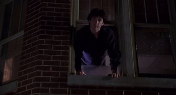 Movie still from “High Fidelity” (2000), directed by Stephen Frears – A man standing on the ledge of a brick building; Medium shot, Low angle