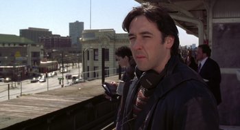 Movie still from “High Fidelity” (2000), directed by Stephen Frears – A man standing next to another man on a train platform; Medium shot, Low angle