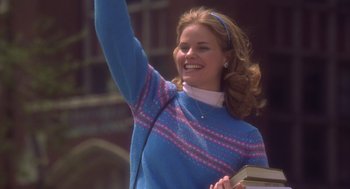 Movie still from “High Fidelity” (2000), directed by Stephen Frears – A woman in a blue sweater holding a book and smiling; Medium shot, Low angle