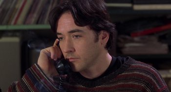 Movie still from “High Fidelity” (2000), directed by Stephen Frears – A man talking on a phone while wearing a sweater; Close Up shot, Low angle
