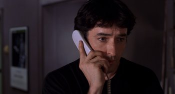 Movie still from “High Fidelity” (2000), directed by Stephen Frears – A man is talking on a phone while wearing a black shirt; Close Up shot, Low angle