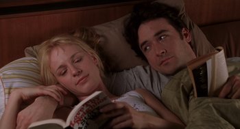 Movie still from “High Fidelity” (2000), directed by Stephen Frears – A man and a woman laying in a bed reading a book; Medium shot, Low angle