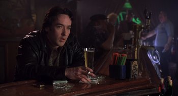 Movie still from “High Fidelity” (2000), directed by Stephen Frears – A man sitting at a bar holding a glass of beer; Medium shot, Low angle