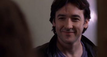 Movie still from “High Fidelity” (2000), directed by Stephen Frears – A man smiling for the camera; Close Up shot, Over the shoulder angle