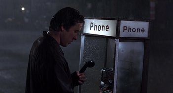 Movie still from “High Fidelity” (2000), directed by Stephen Frears – A man holding a microphone in front of a phone booth in the rain; Close Up shot, Low angle
