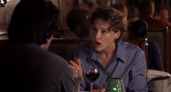 Movie still from “High Fidelity” (2000), directed by Stephen Frears – A woman sitting at a table with a glass of red wine in front of her; Close Up shot, Over the shoulder angle