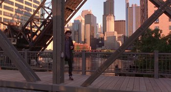 Movie still from “High Fidelity” (2000), directed by Stephen Frears – A man is standing on a bridge with a city in the background; Extreme Wide shot, High angle