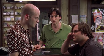 Movie still from “High Fidelity” (2000), directed by Stephen Frears – A group of men sitting at a table talking to each other; Medium shot, Over the shoulder angle