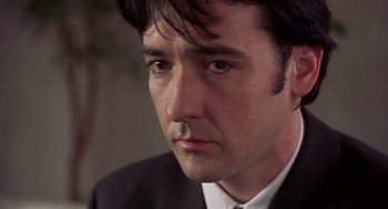 Movie still from “High Fidelity” (2000), directed by Stephen Frears – A person wearing a suit and tie; Close Up shot, Low angle