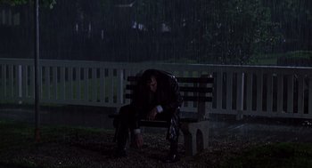 Movie still from “High Fidelity” (2000), directed by Stephen Frears – A man sitting on top of a wooden bench in the rain; Wide shot, Low angle