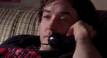 Movie still from “High Fidelity” (2000), directed by Stephen Frears – A young man is holding a phone up to his ear; Close Up shot, Low angle