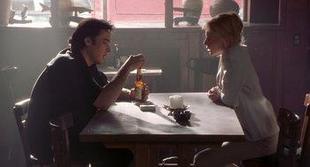 Movie still from “High Fidelity” (2000), directed by Stephen Frears – A man and a woman sitting at a table with a beer; Medium shot, Low angle