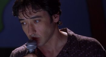 Movie still from “High Fidelity” (2000), directed by Stephen Frears – A person holding a microphone; Close Up shot, Low angle