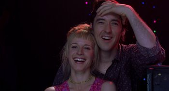 Movie still from “High Fidelity” (2000), directed by Stephen Frears – A man and a woman smiling for the camera; Close Up shot, Low angle