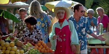 Movie still from “High Heels” (1991), directed by Pedro Almodóvar – A woman wearing a straw hat stands in front of a fruit stand; Medium shot, Over the shoulder angle
