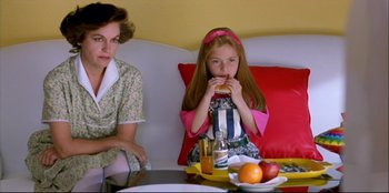 Movie still from “High Heels” (1991), directed by Pedro Almodóvar – A woman sitting next to a little girl eating a sandwich; Medium shot, High angle