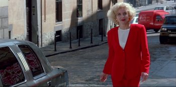 Movie still from “High Heels” (1991), directed by Pedro Almodóvar – A woman in a red suit walking down the street; Medium shot, Low angle