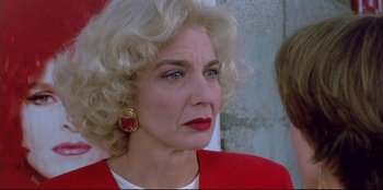 Movie still from “High Heels” (1991), directed by Pedro Almodóvar – An older woman with blonde hair wearing a red jacket; Close Up shot, Low angle