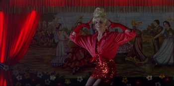 Movie still from “High Heels” (1991), directed by Pedro Almodóvar – A woman in a red shirt and a red sequined skirt; Medium shot, Low angle