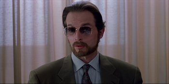 Movie still from “High Heels” (1991), directed by Pedro Almodóvar – A person wearing a suit and tie; Close Up shot, Low angle