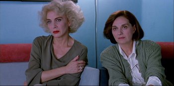 Movie still from “High Heels” (1991), directed by Pedro Almodóvar – Two women sitting next to each other in a room; Close Up shot, Low angle