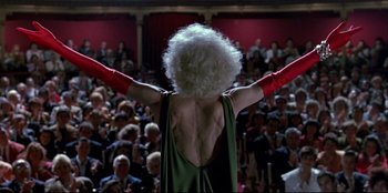Movie still from “High Heels” (1991), directed by Pedro Almodóvar – A person with a white wig and long red gloves; Medium shot, Low angle