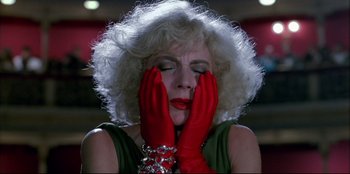 Movie still from “High Heels” (1991), directed by Pedro Almodóvar – A woman with red gloves covering her face with her hands; Close Up shot, Low angle
