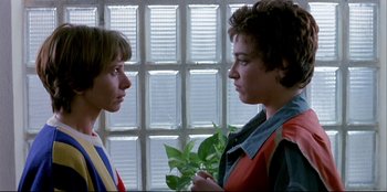 Movie still from “High Heels” (1991), directed by Pedro Almodóvar – Two young people standing next to each other in front of a window; Close Up shot, Over the shoulder angle