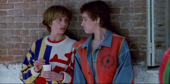 Movie still from “High Heels” (1991), directed by Pedro Almodóvar – Two young men standing next to a brick wall; Medium shot, Low angle