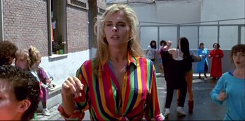 Movie still from “High Heels” (1991), directed by Pedro Almodóvar – A woman wearing a colorful shirt is smoking a cigarette; Medium shot, Low angle