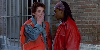 Movie still from “High Heels” (1991), directed by Pedro Almodóvar – Two people standing next to each other near a brick wall; Close Up shot, Low angle