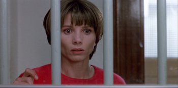 Movie still from “High Heels” (1991), directed by Pedro Almodóvar – A woman in a red shirt behind a metal fence; Close Up shot, Low angle
