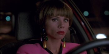 Movie still from “High Heels” (1991), directed by Pedro Almodóvar – A person in a car wearing a pink shirt; Close Up shot, Over the shoulder angle