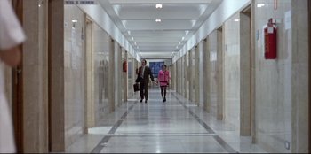 Movie still from “High Heels” (1991), directed by Pedro Almodóvar – Two people walking down a long hallway in a building; Extreme Wide shot, High angle