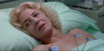 Movie still from “High Heels” (1991), directed by Pedro Almodóvar – A woman laying in a hospital bed with an electric device attached to her chest; Close Up shot, High angle