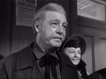Movie still from “High Noon” (1952), directed by Fred Zinnemann – An older man and a young woman are posing for a picture; Close Up shot, Low angle