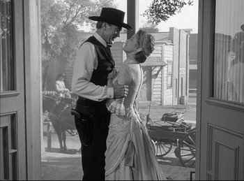 Movie still from “High Noon” (1952), directed by Fred Zinnemann – A man and a woman dressed in western garb; Medium shot, Over the shoulder angle