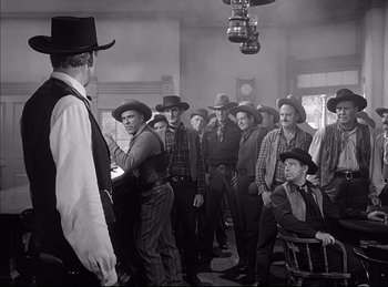 Movie still from “High Noon” (1952), directed by Fred Zinnemann – A group of men standing in a room; Wide shot, Over the shoulder angle